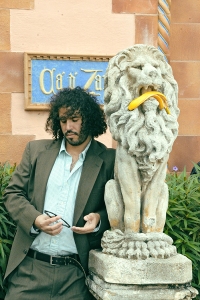 Daniel Bejar Destroyer holding sunglasses against a lion statue with a banana peel in it's mouth.